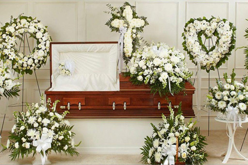 arreglos florales blancos sobre un ataud cafe